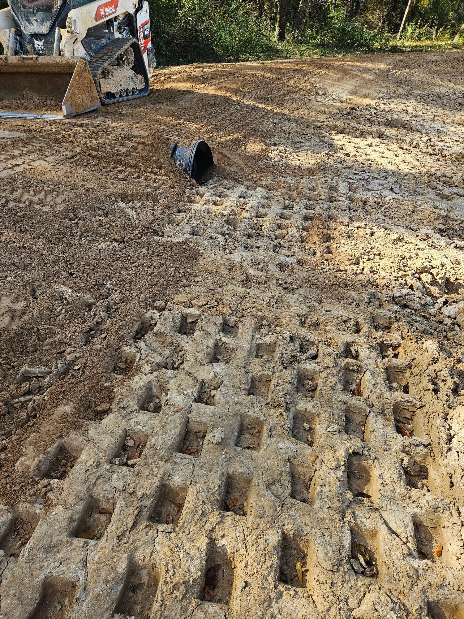 Erosion control silt fencing installed along construction site perimeter with swale drainage system