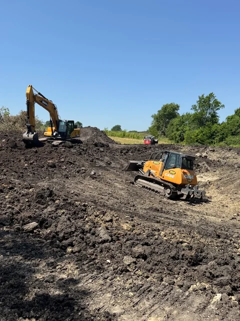 Tracked excavator and dump truck performing soil excavation and grading on open site