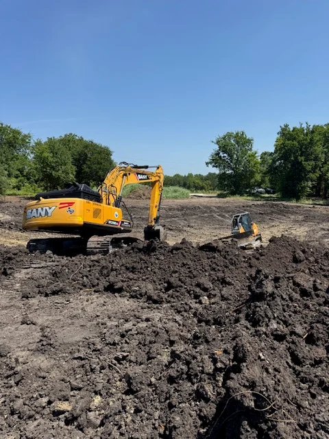 Yellow SANY excavator performing site excavation and soil grading on open dirt lot