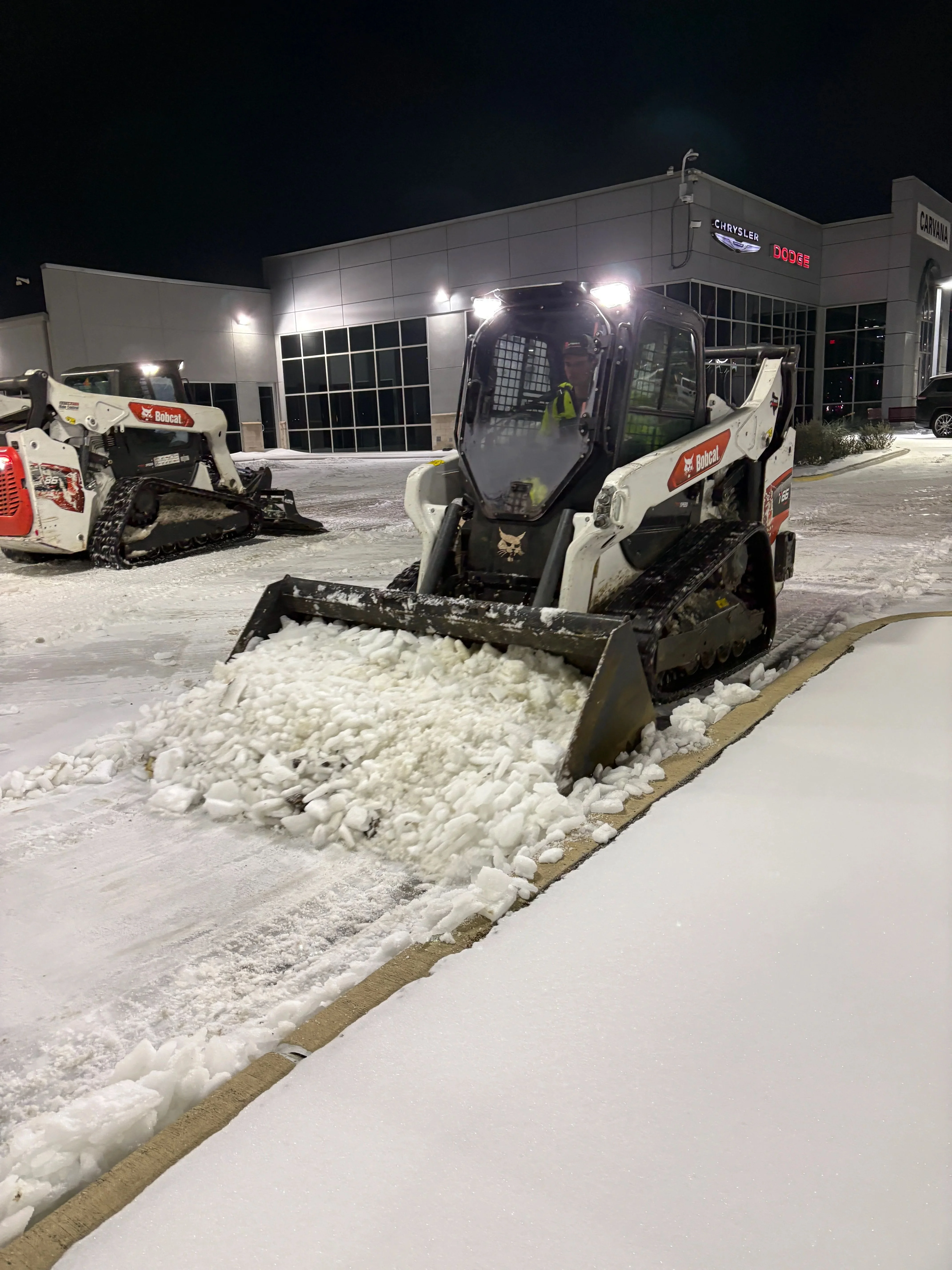 A cleared commercial parking lot and sidewalk in Dallas, Texas after a winter ice storm, with treated pavement and open entryways visible. Snow and ice have been removed from the surface, leaving clean, accessible paths for foot and vehicle traffic.